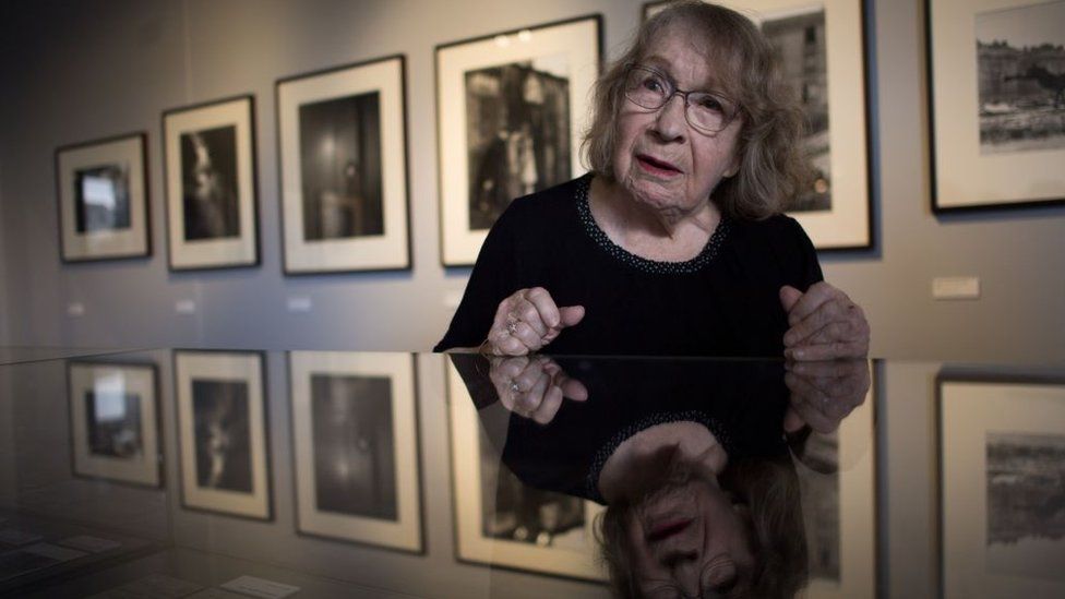 Swiss-French photographer Sabine Weiss poses in front of her pictures on July 16, 2020 in Vannes as she visits a retrospective exhibition of her work