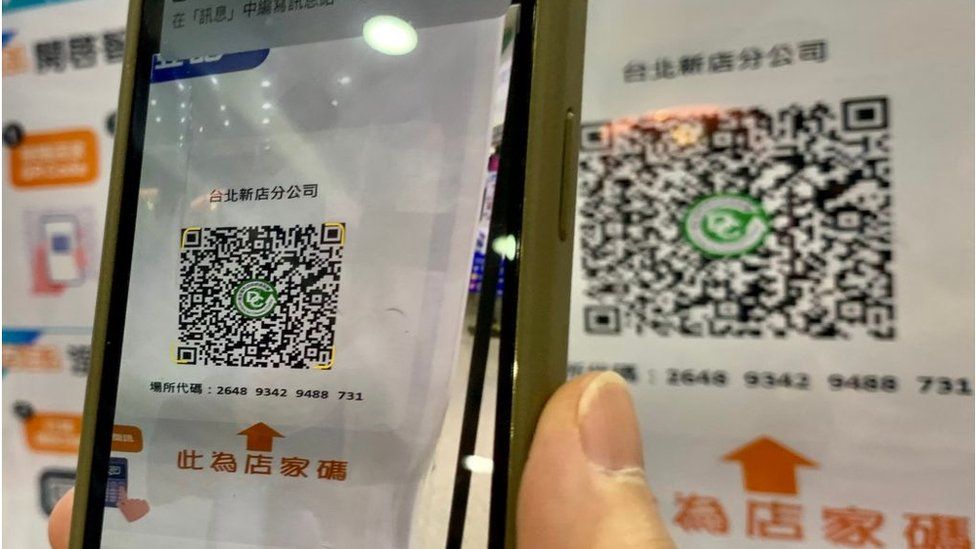 A local resident scans a QR code of a government-made app to register her personal identity before entering a shopping mall in New Taipei City