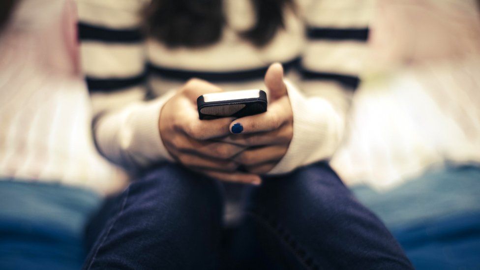 A stock image of a teenage girl using a smart phone only her hands are visible