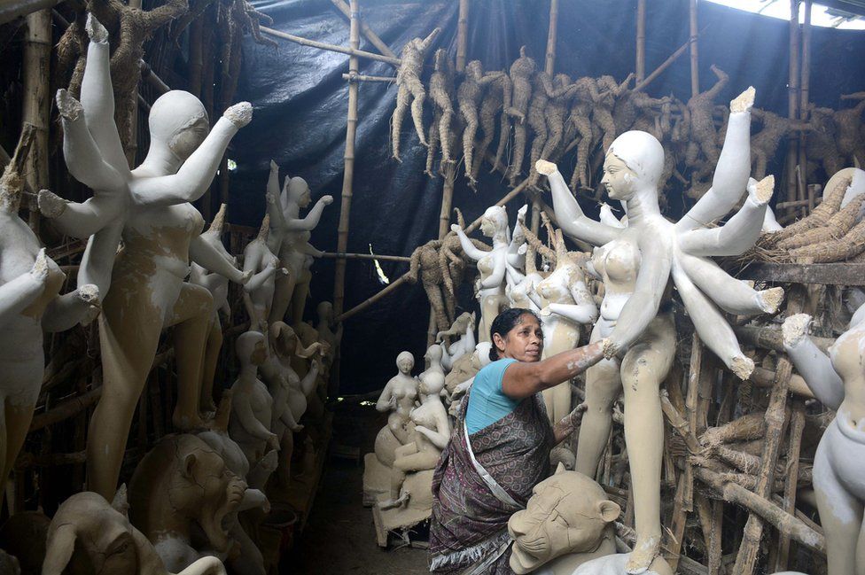 A woman paints sculptures of goddesses