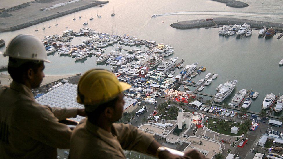 Индийские рабочие наблюдают за открытием международного бот-шоу в Дубае с 50-го этажа башни, которая возводится за Дубайским международным морским клубом, 14 марта 2006 г.