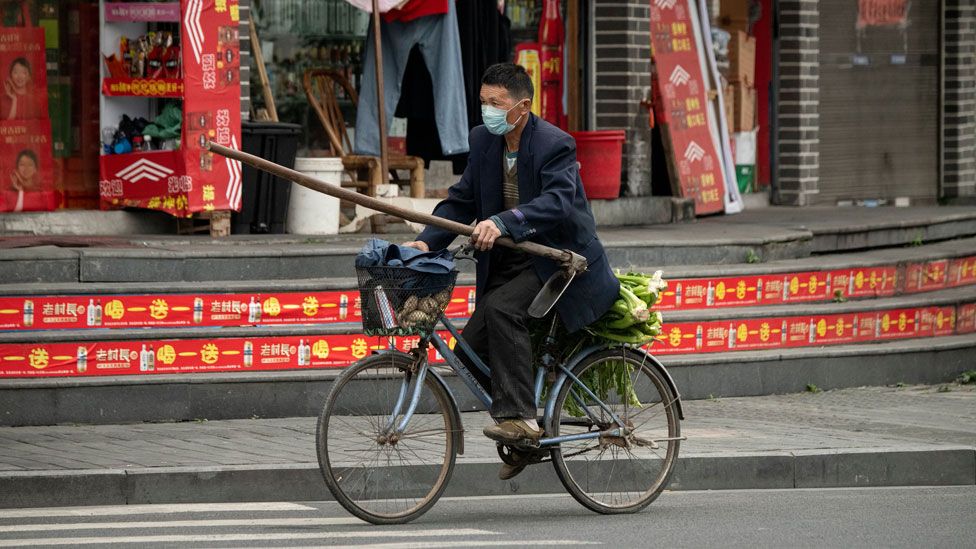 Un hombre en bicicleta con mascarilla en las calles de Wenzhou, China