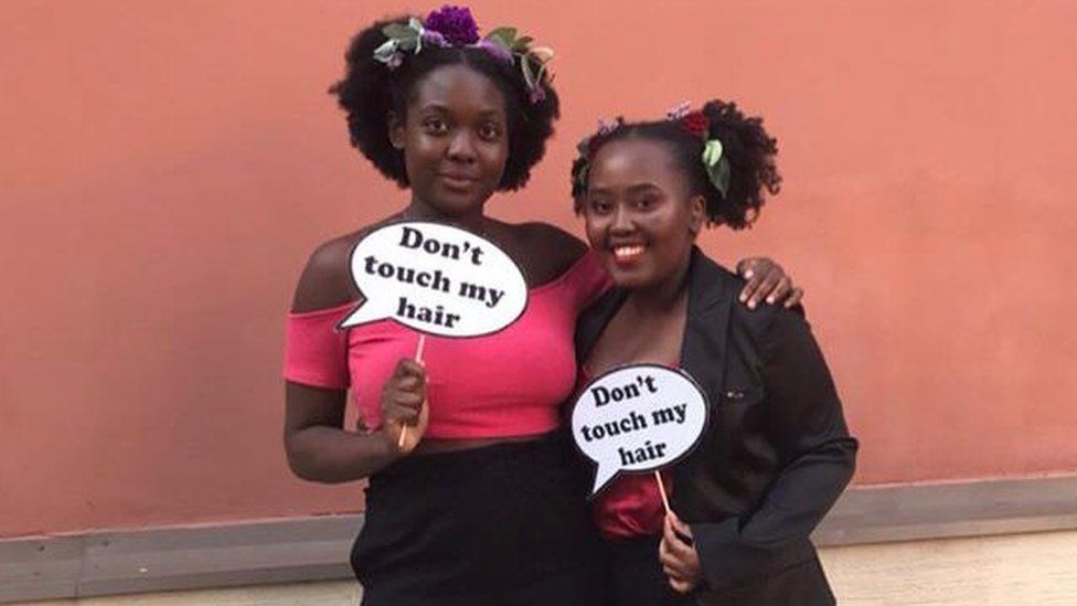 Two women with "don't touch my hair" signs