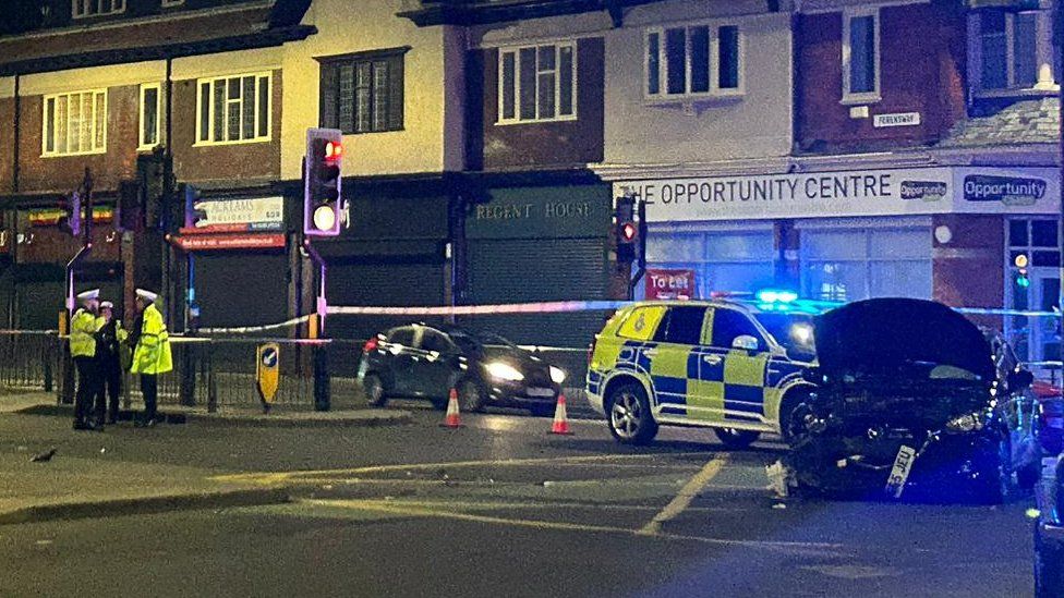 Police officers talking at traffic lights near crashed cars