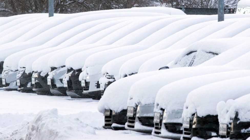 A thick blanket of snow lies on cars at a used car dealer in Rehna, Germany