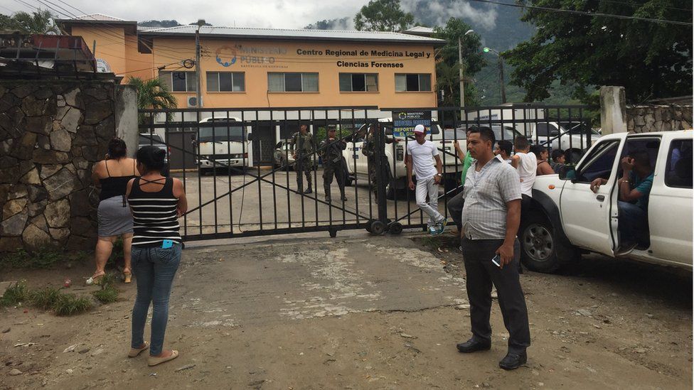 People stand outside a morgue guarded by military men in San Pedro Sula