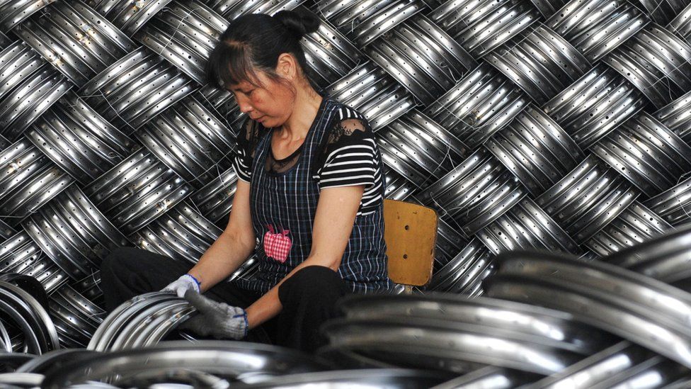 A woman works in a factory making steel hubs in China