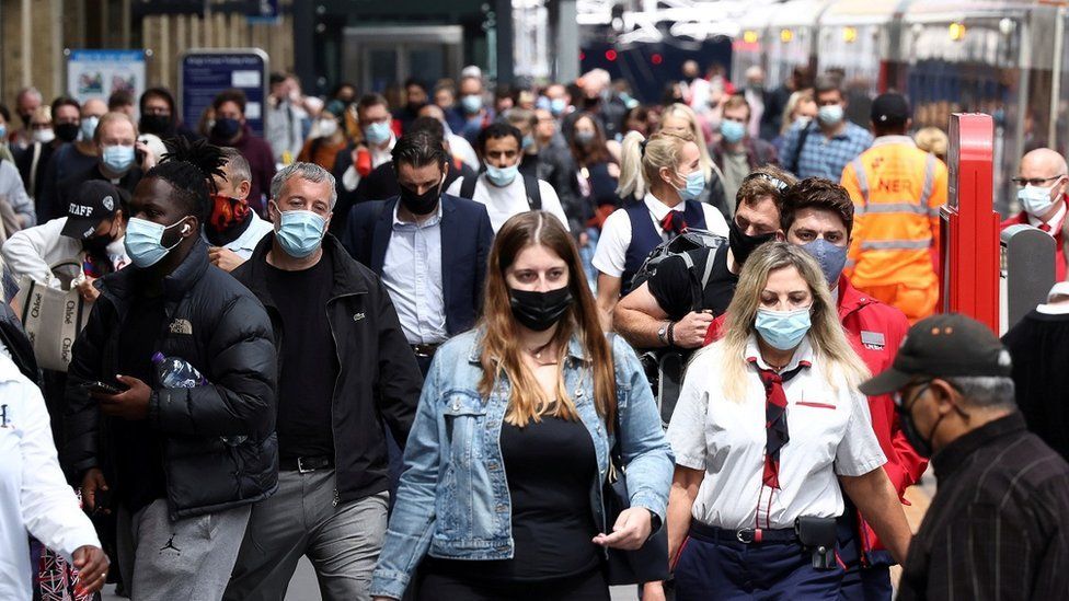 People wearing face masks walk at King's Cross Station