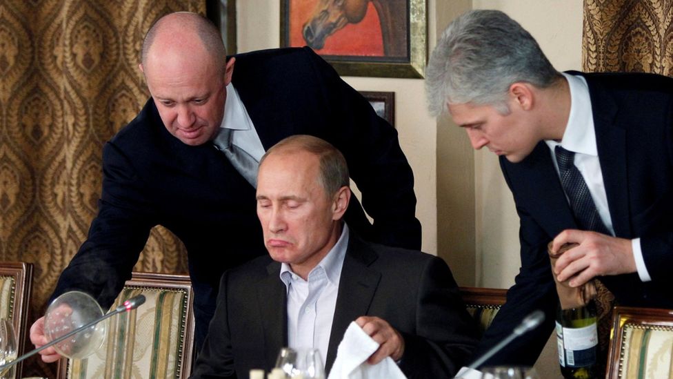 Yevgeny Prigozhin helping Russian President Vladimir Putin at a dinner table. Photo: 2011