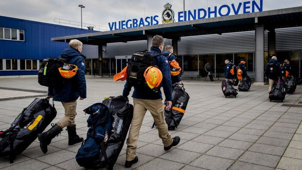 Двое голландских пожарных идут в аэропорт с сумками и касками