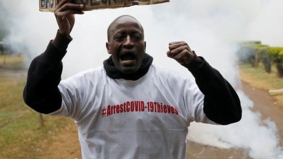 A protester holds a placard as he is engulfed by tear gas during a demonstration against suspected corruption in the response of the Kenyan government to the coronavirus disease (COVID-19) outbreak, in Nairobi, Kenya, August 21, 2020