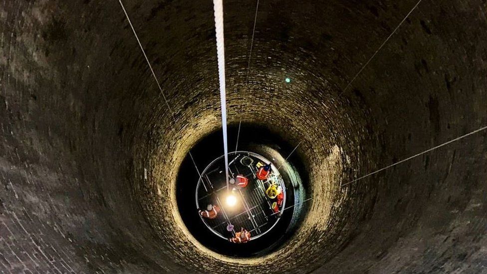 A cradle descending into the darkness of the 241m deep shaft