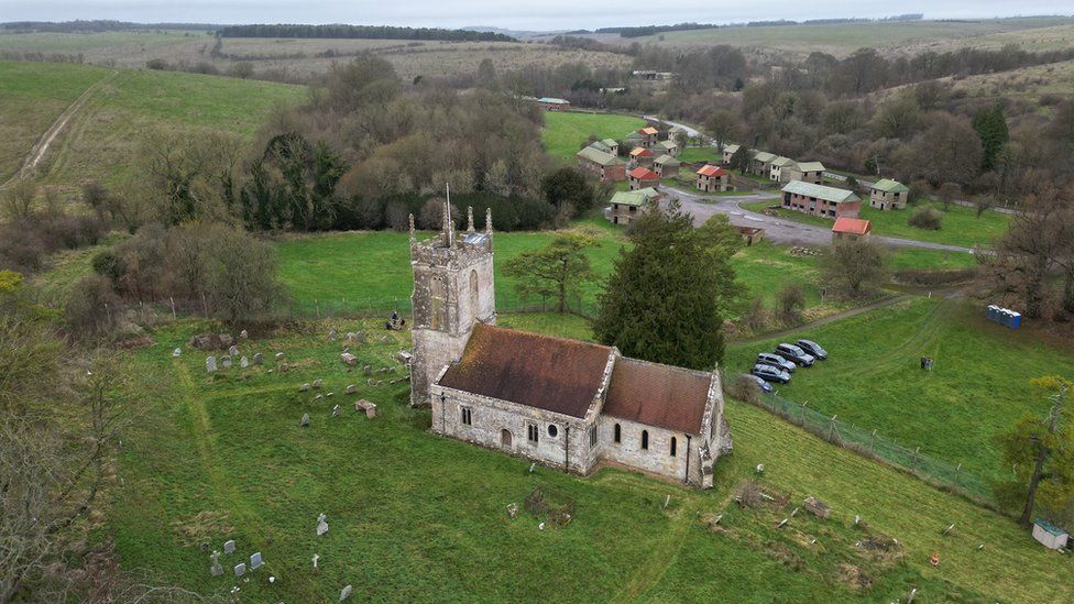 A drone image of St Giles Church with the army buildings of the former village in the background