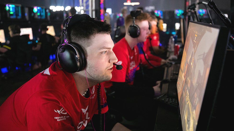 A London Royal Ravens competitor, wearing headphones and a red shirt, playing Call of Duty on a computer screen