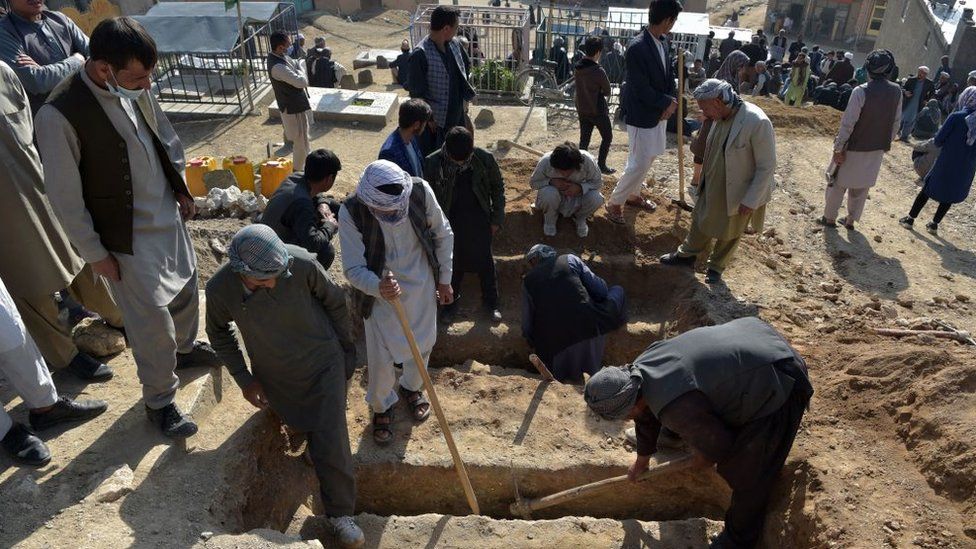 People bury victims of a series of blasts near a school in Kabul which killed more than 50 people
