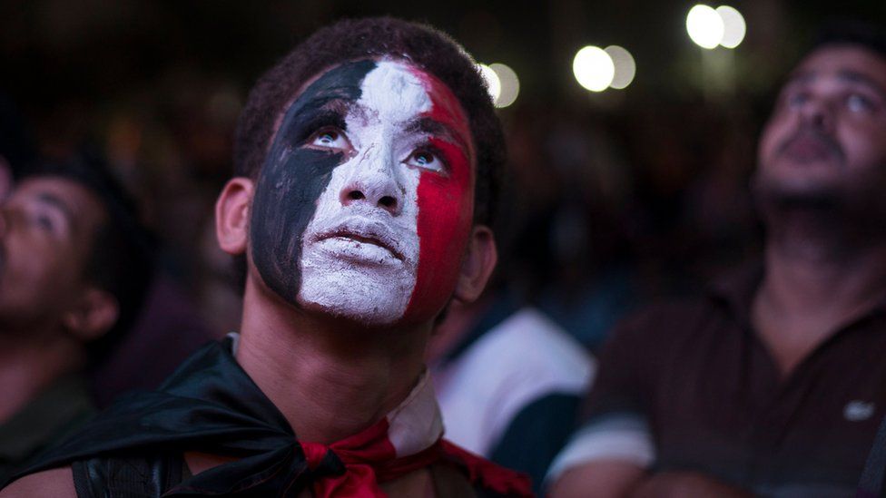 Egyptian men watch their natiional team play Congo Brazzaville on a big TV screen