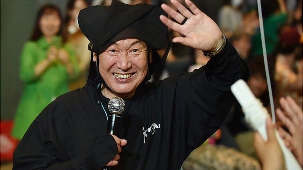 Japanese designer Kansai Yamamoto waves to the audience after his fashion event 'super energy !!' in Tokyo on June 12, 2015.