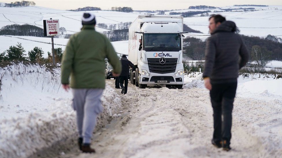 Motorists gather by a stuck HGV along the snow-covered A515 near Biggin, in the Peak District, Derbyshire