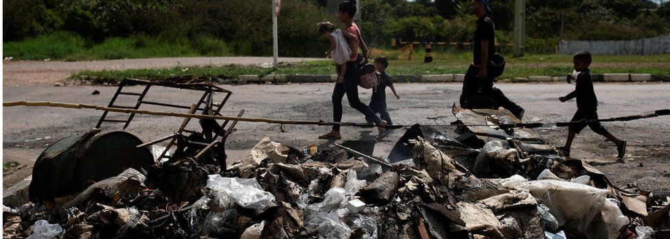 Venezuelans walk past belongings and tents burned by civilians at the Pacaraima border control, Roraima State, Brazil August 19, 2018.