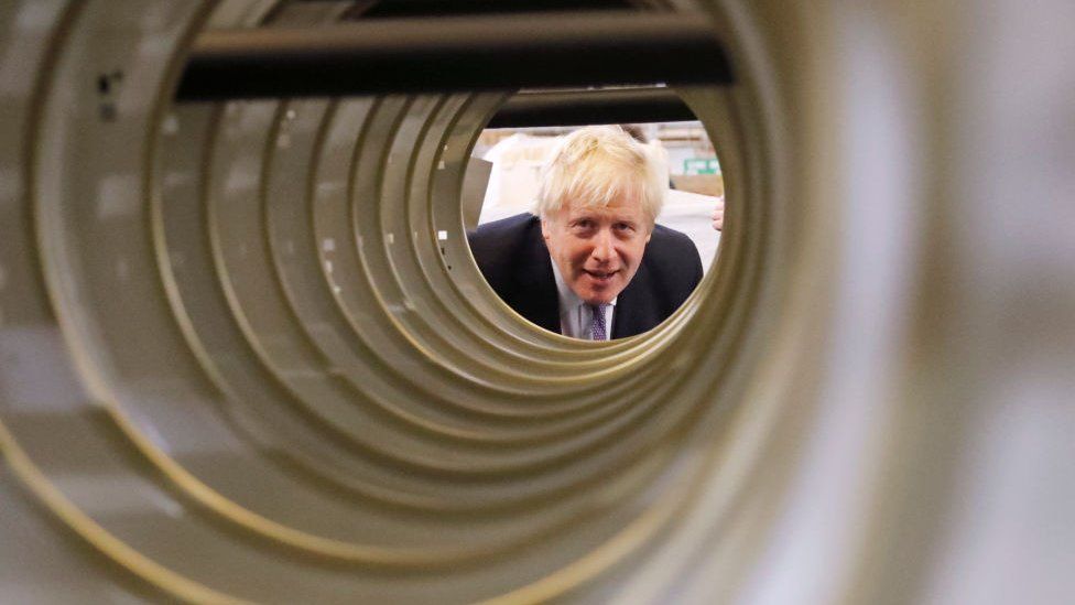 Boris Johnson looking down tube in factory