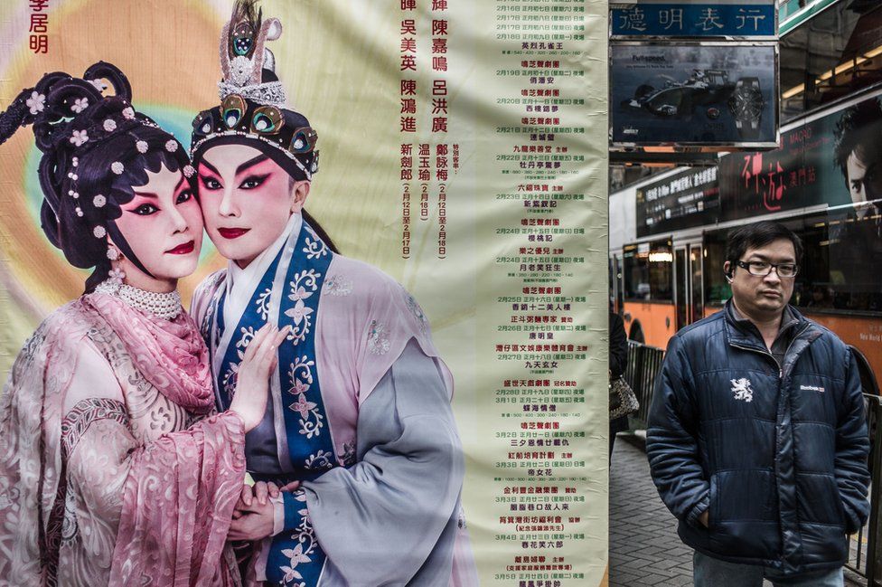 A man walks past a billboard advertising for the programme of a Cantonese Opera house in Hong Kong on January 15, 2013.