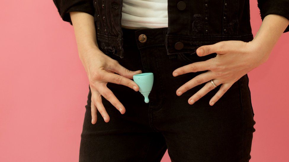 A crop of a woman holding menstrual cup to pelvis