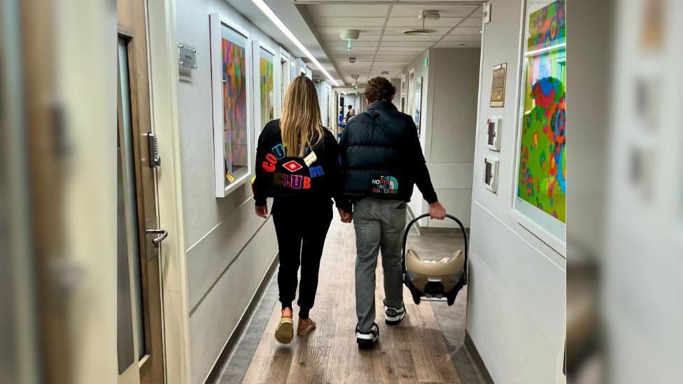 Olly Murs, who is holding a car seat with the baby inside, walks with Amelia