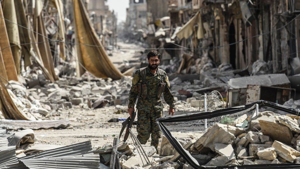 A member of the Syrian Democratic Forces walks through the debris in the old city centre of Raqqa
