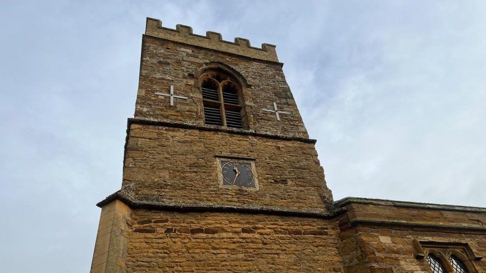 Stone tower of a 19th century church, with a small square clock face