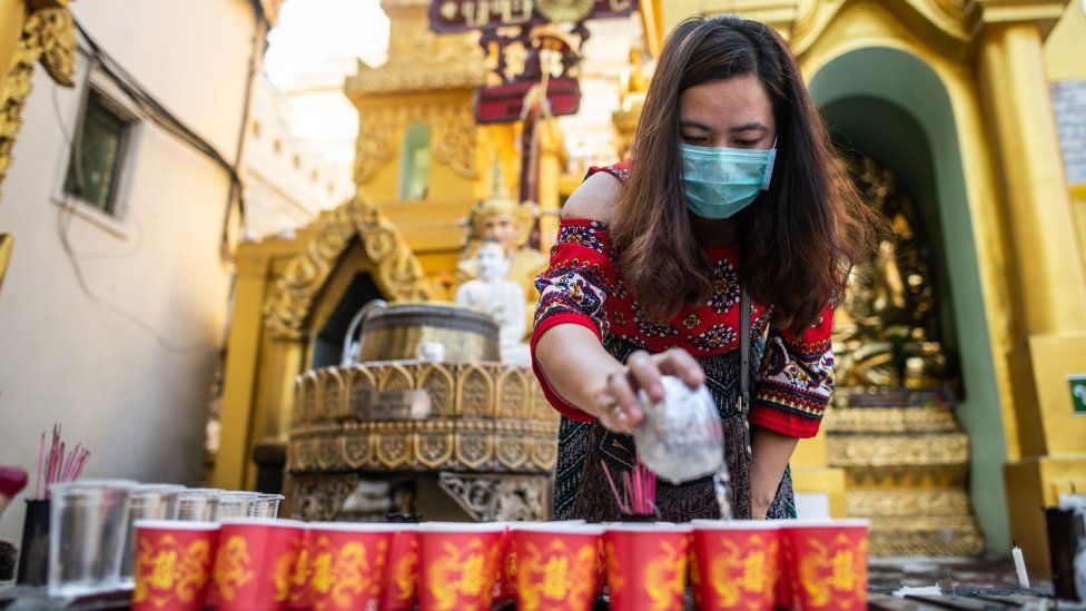 A woman wearing face mask, as she visits Shwedagon pagoda in Yangon