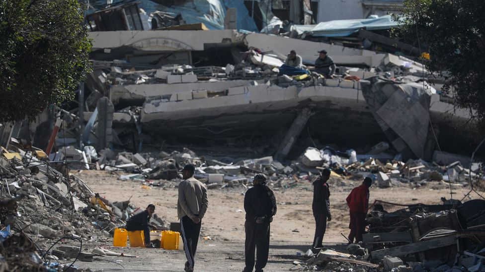 People walk next to destroyed houses on 17 February