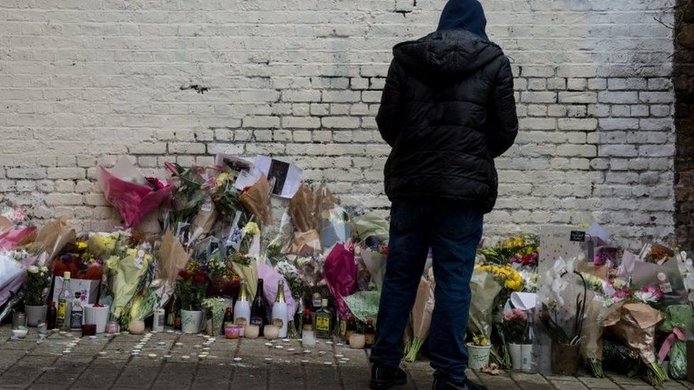 A man looking at flowers in London, left where 18-year-old Israel Ogunsola was stabbed