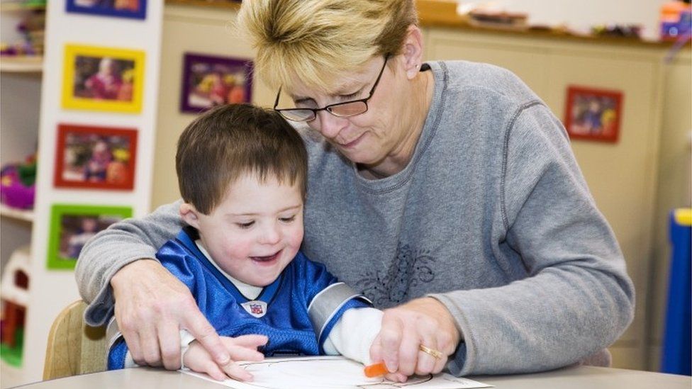 Teacher helps a boy to write at a school for children with special educational needs.
