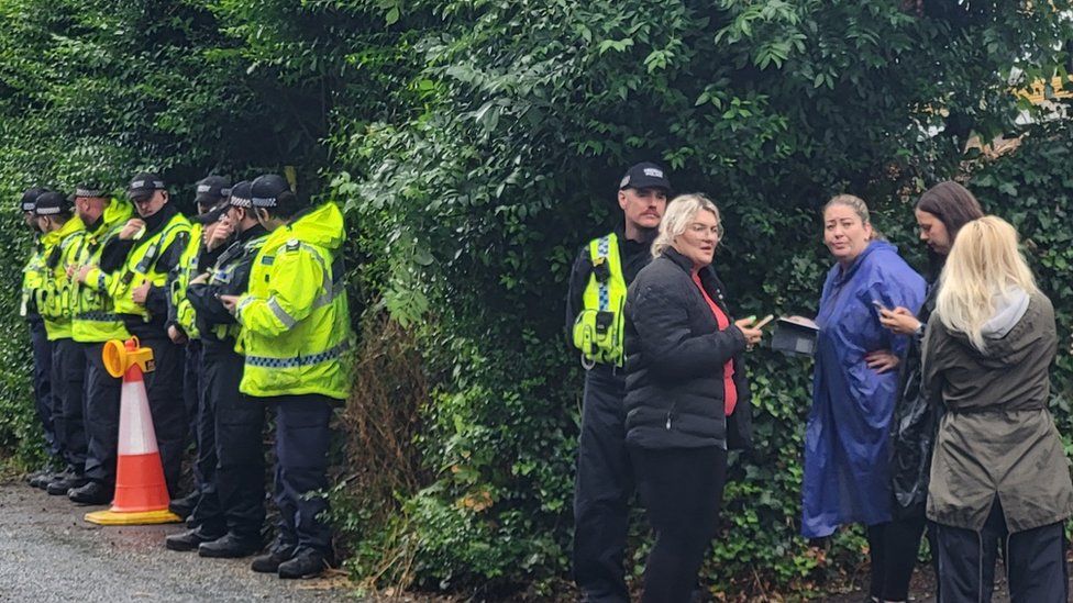 Police and protestors near a hedge at the hotel on Monday