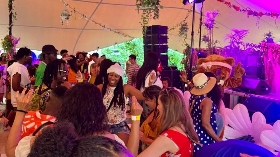 Dancers dance in front of a DJ booth at Afrofest