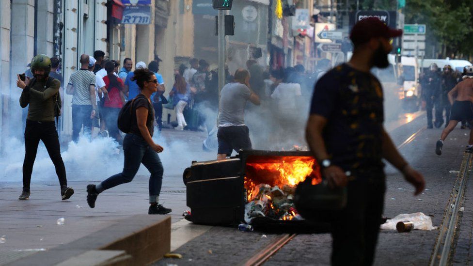 Protesters run from launched tear gas canisters during clashes with police in Marseille, southern France on July 1, 2023,