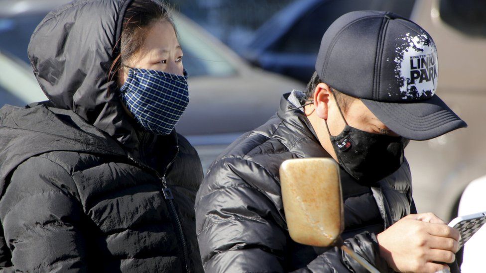 A woman and a man on a scooter wear protective masks in Beijing on 18 December, 2015