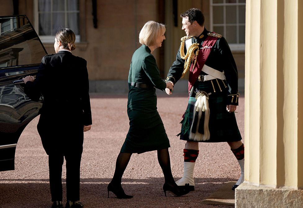 Уходящего премьер-министра Лиз Трасс встречает конюший короля Карла III подполковник Джонни Томпсон по прибытии в Букингемский дворец 25 октября 2022 года