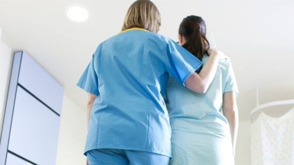 A nurse comforts a woman in a hospital