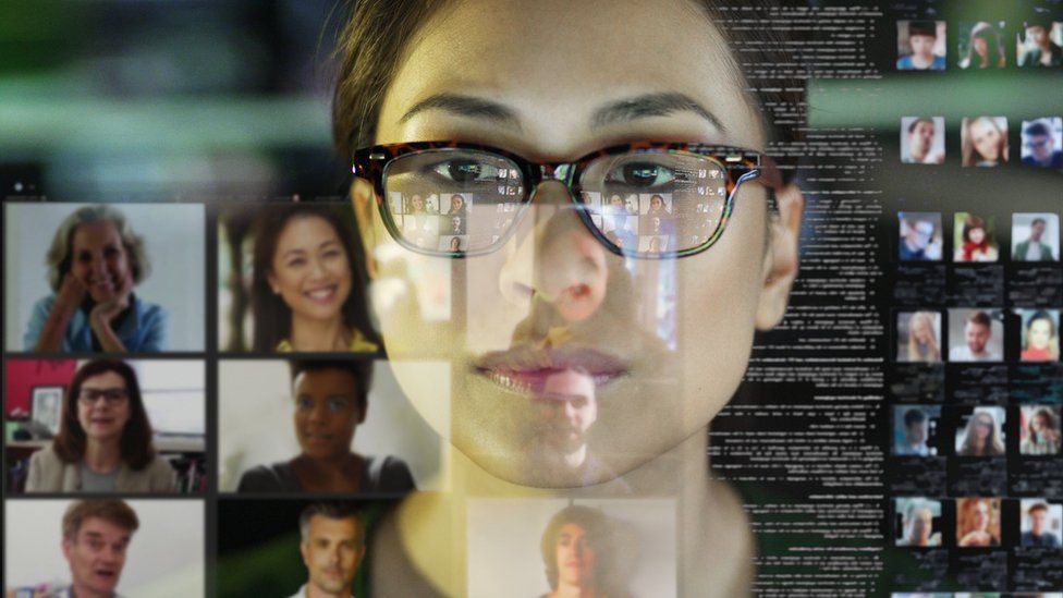 Woman's face reflected in a video conference screen showing several other faces