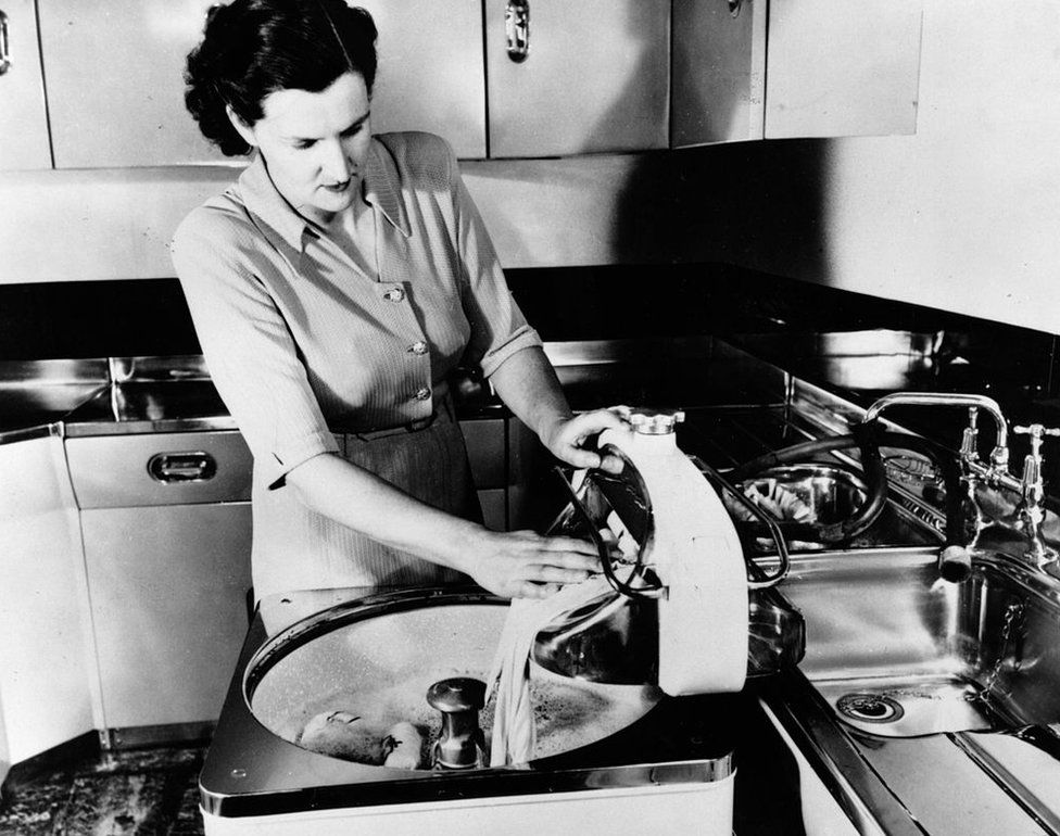 A woman demonstrating an early electric washing machine, circa 1950