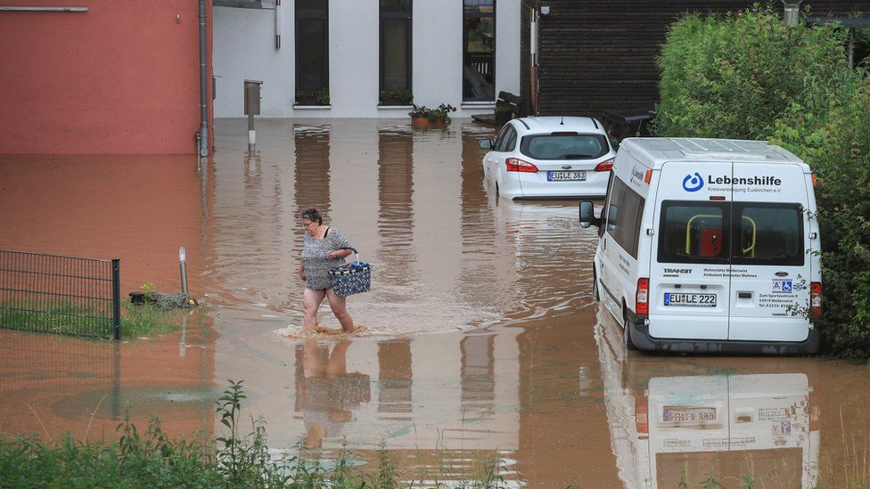 A woman wades across floodwater as she goes out shopping following heavy rainfall