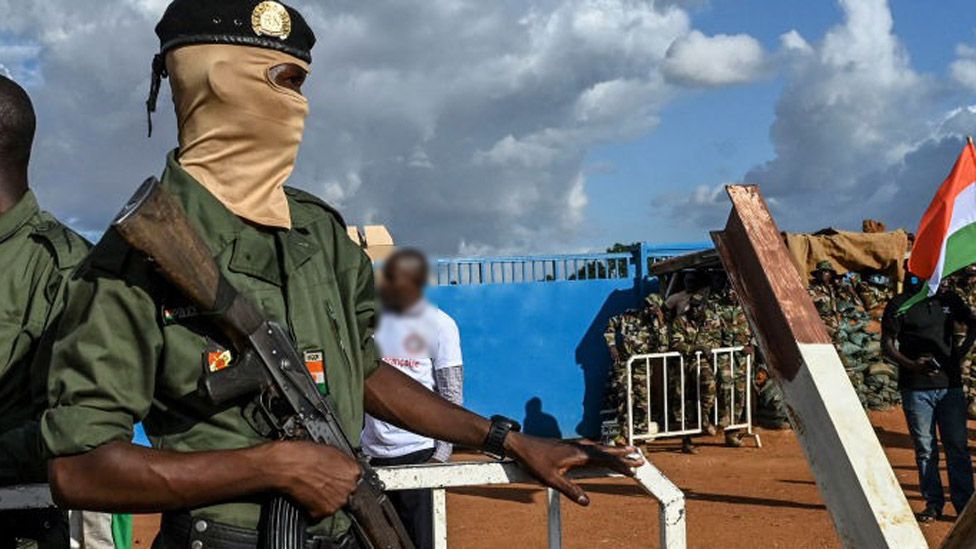 Niger's security officers stand guard as supporters of Niger's National Council of Safeguard of the Homeland (CNSP) gather outside Niger and French airbase in Niamey on September 3, 2023, to demand the departure of the French army from Niger.