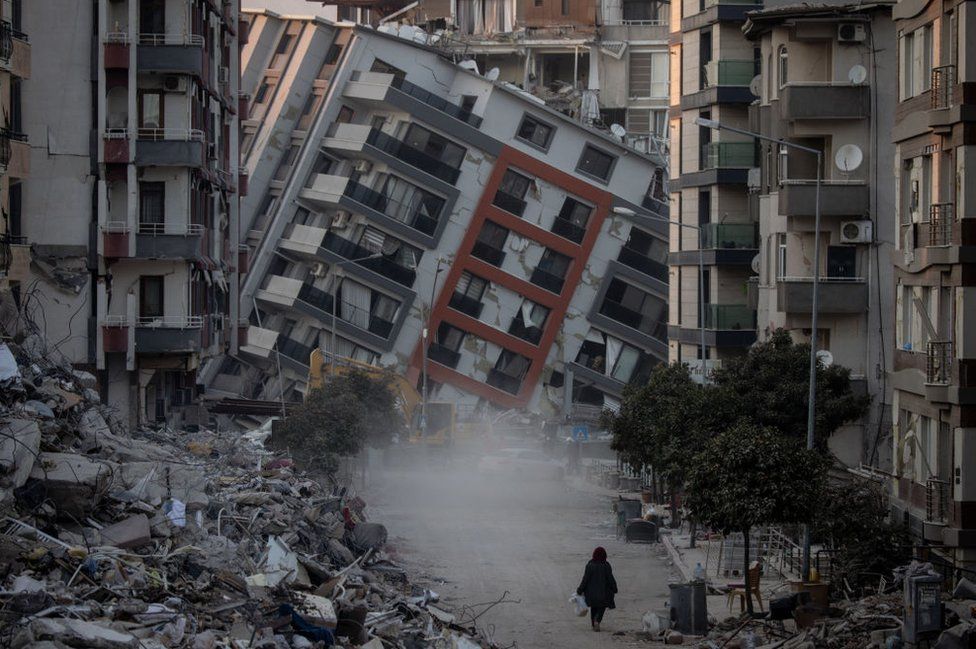 Një grua ecën në një rrugë mes ndërtesave të shkatërruara më 17 shkurt 2023 në Hatay, Turqi.