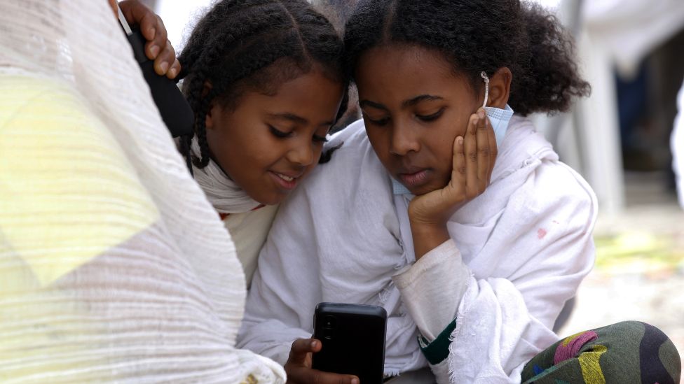 Two girls looking at out a mobile phone in Addis Ababa, Ethiopia - Friday 30 April 2021