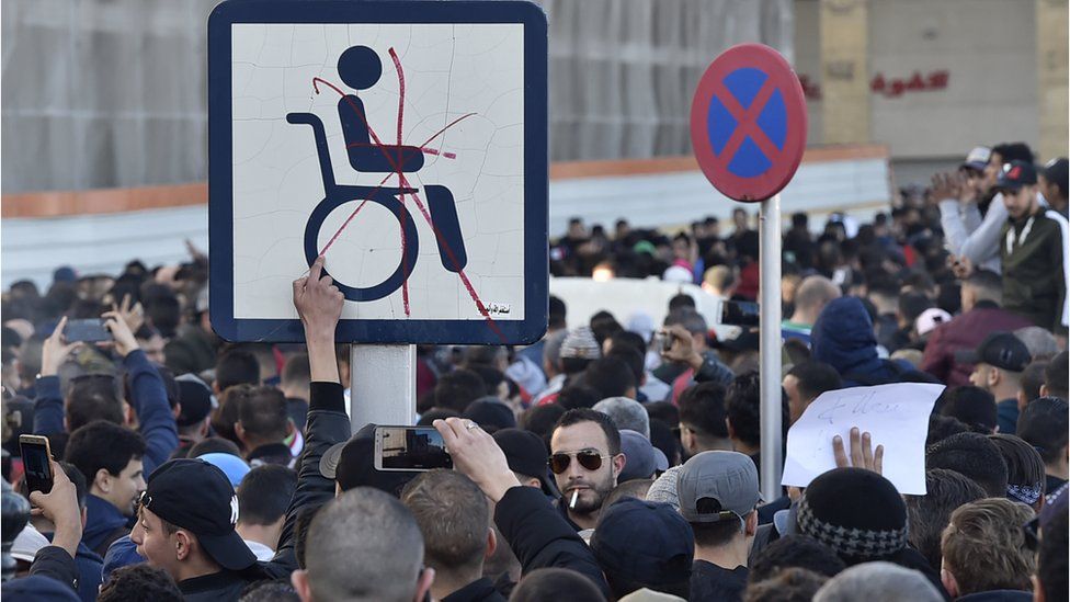 Protesters put a red cross through a wheelchair access sign in Algiers, Algeria