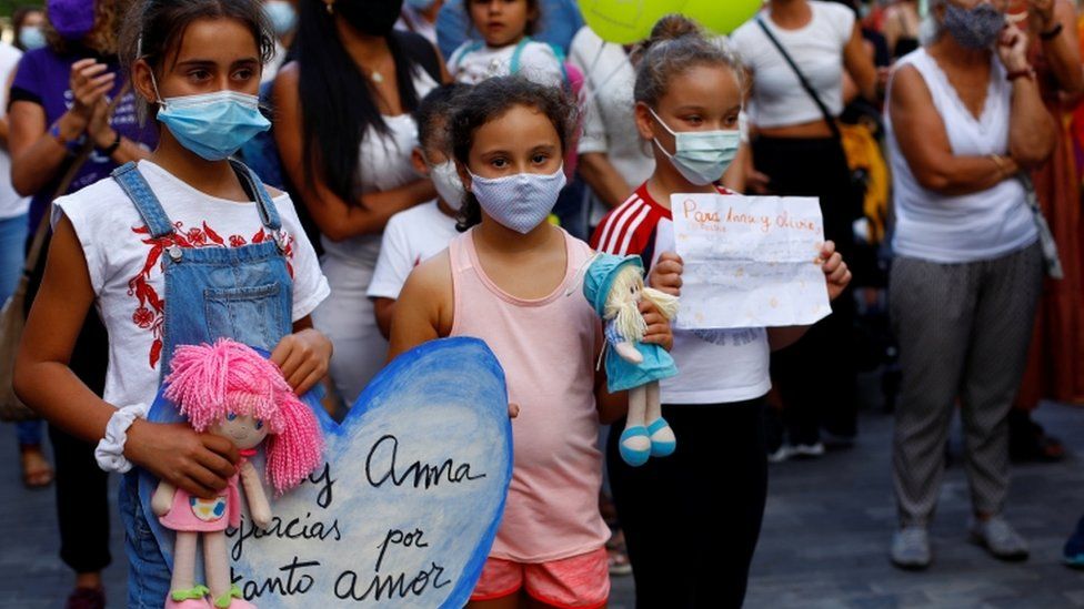 Children at a protest holding dolls and signs