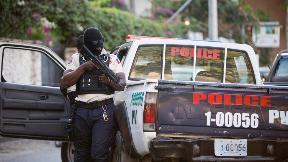 Haitian police officer holding an automatic firearm next to his patrol vehicle in Petion-Ville, Haiti, Thursday, Jan 5, 2017