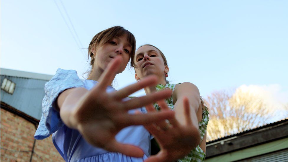 Louise and Kristen holding their hands up to the camera