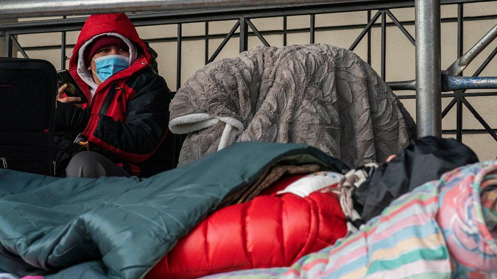 Migrants cover themselves during cold temperatures outside the Watson Hotel, which is being used to house asylum seekers, in New York, U.S., February 1, 2023